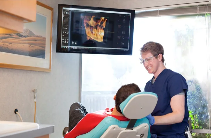 Dr. Mynsberge and a patient with a screen showing a 3D model of the patient's skull