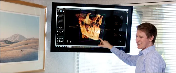 Dr. Mynsberge pointing to a screen showing a 3D model of a patient's skull