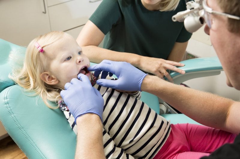 Dr. Mynsberge and an assistant examining the mouth of a child patient